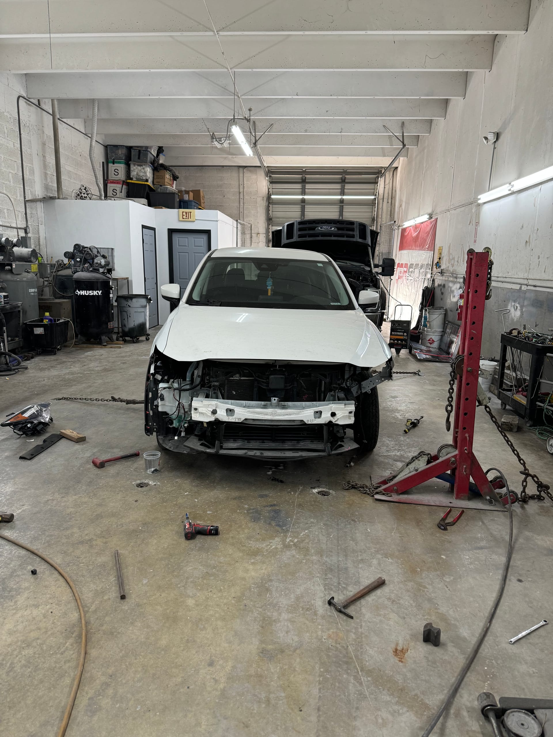 White Mazda CX-5 with the front bumper, grille and headlights removed before repair