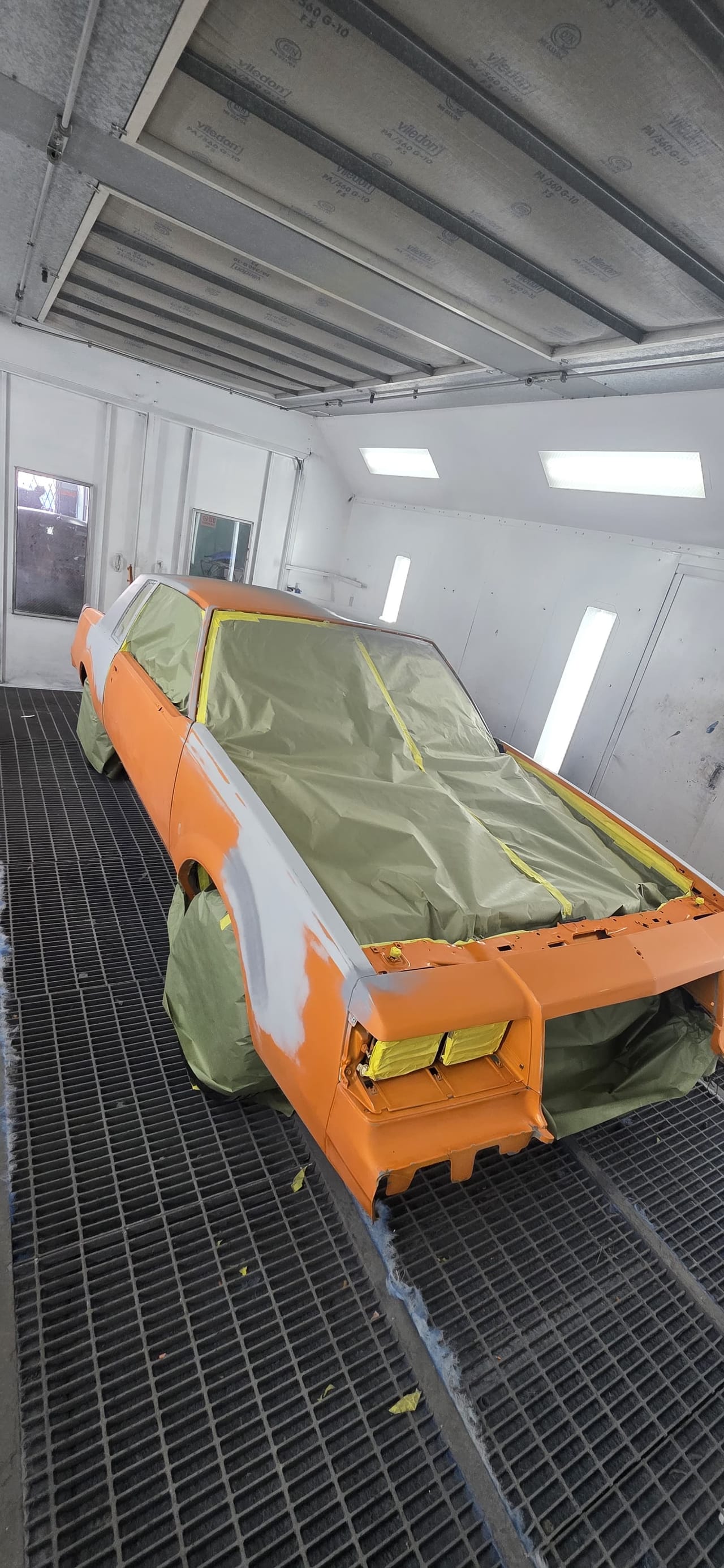Classic Chevy Malibu stripped to primer, rear view inside the paint booth