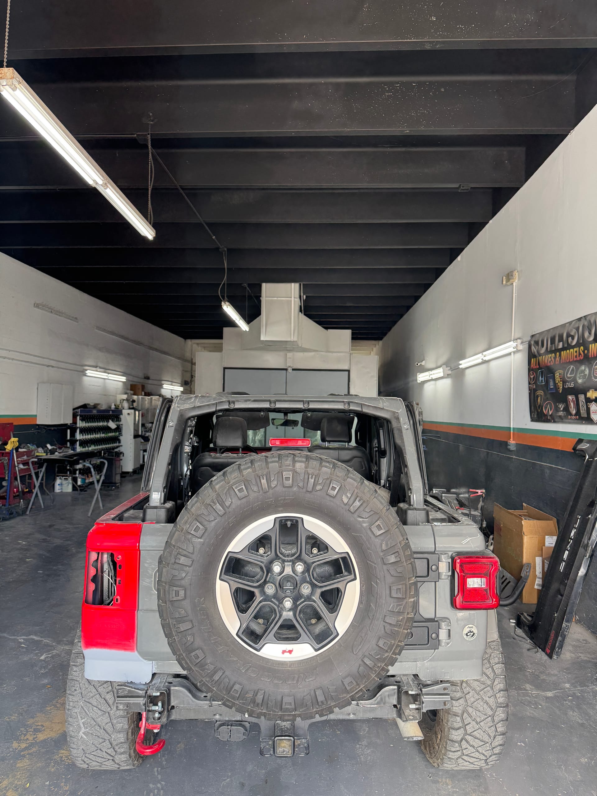Grey Jeep Wrangler with a replacement rear quarter panel in red primer before paint